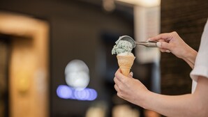 Une personne qui sert de la glace à la cuillère dans un cornet.
