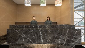 Un comptoir d’accueil avec un plateau en marbre et trois suspensions décoratives.