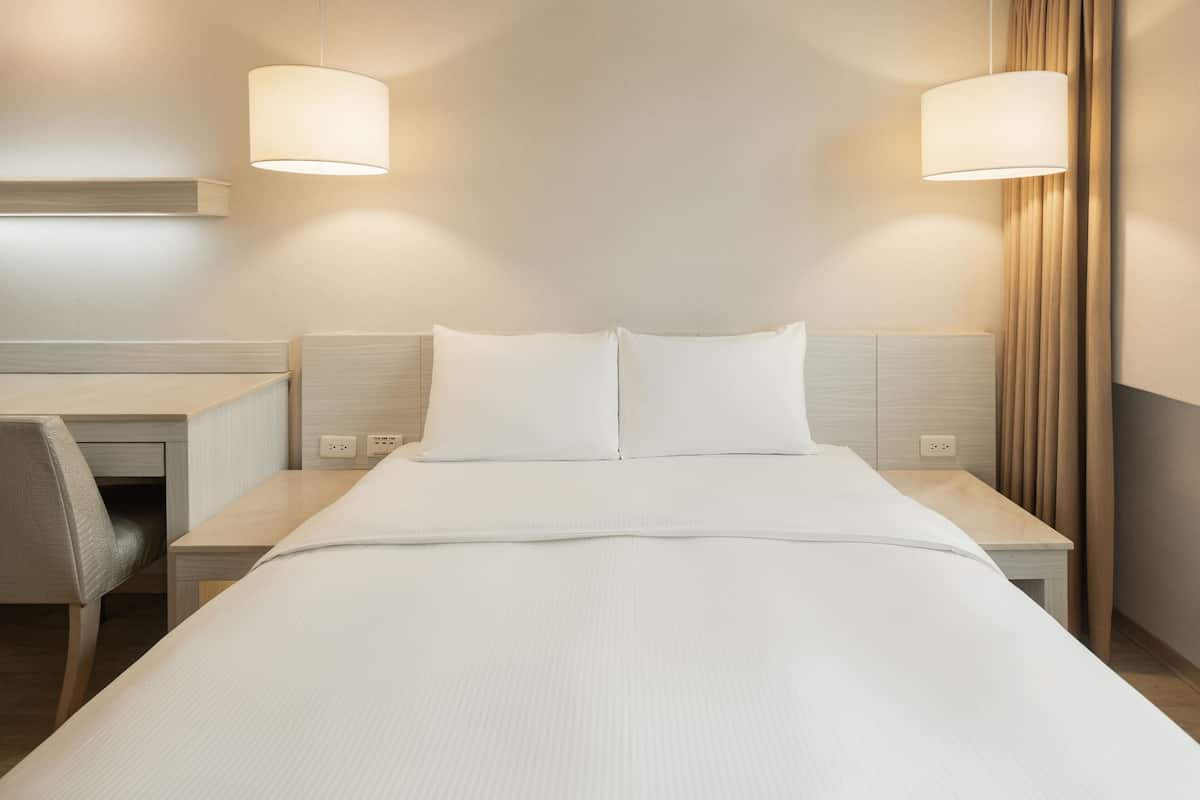 Een hotelkamer met een bed, nachtkastjes, een bureau en twee wandlampen.