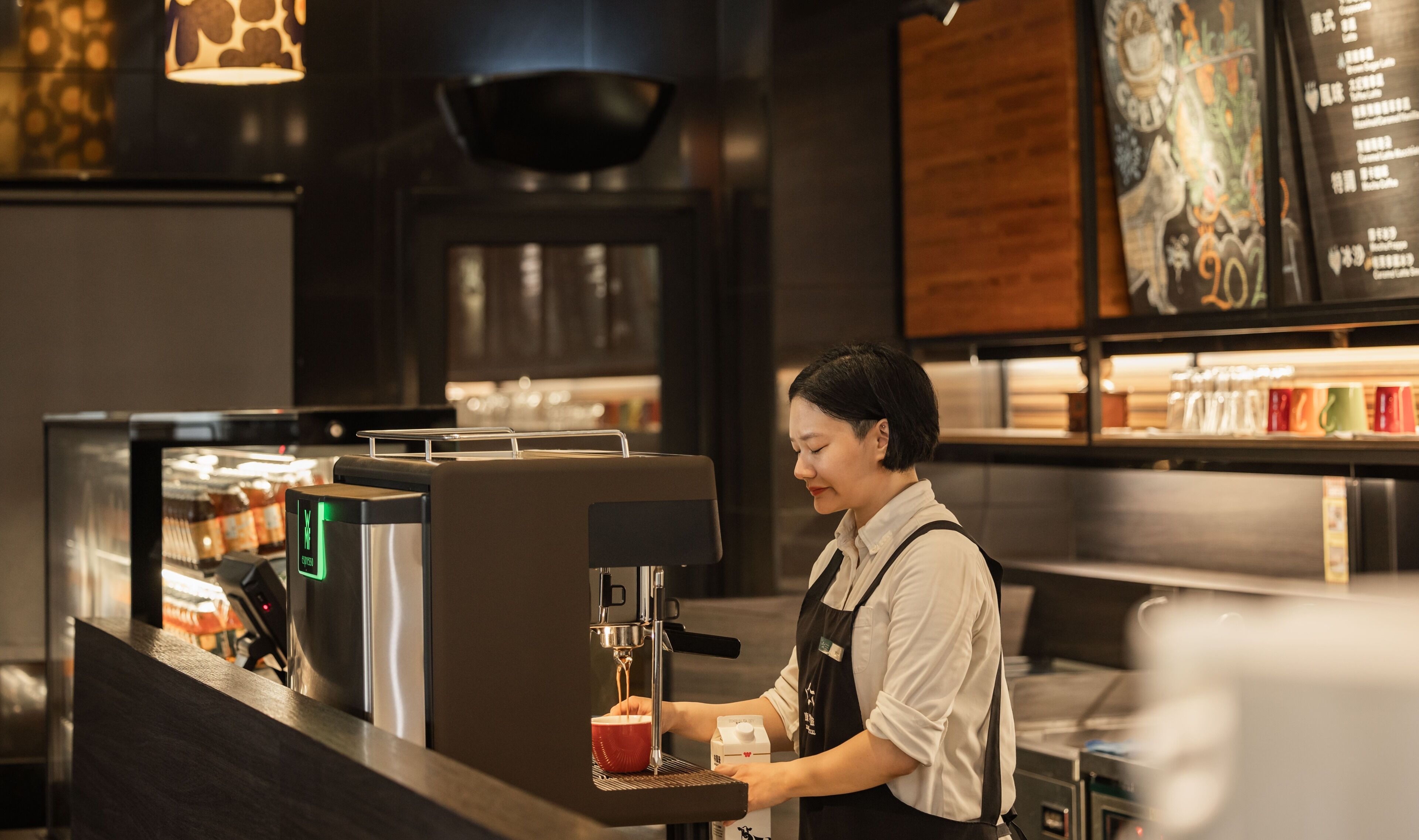 A barista at a coffee machine in a cafe.
