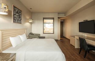 Una camera d'albergo con un letto, una scrivania, una televisione e una finestra.