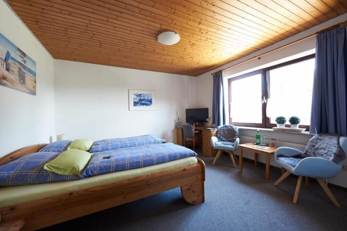Een gezellige kamer met een houten bed, een bureau, een stoel en een televisie.