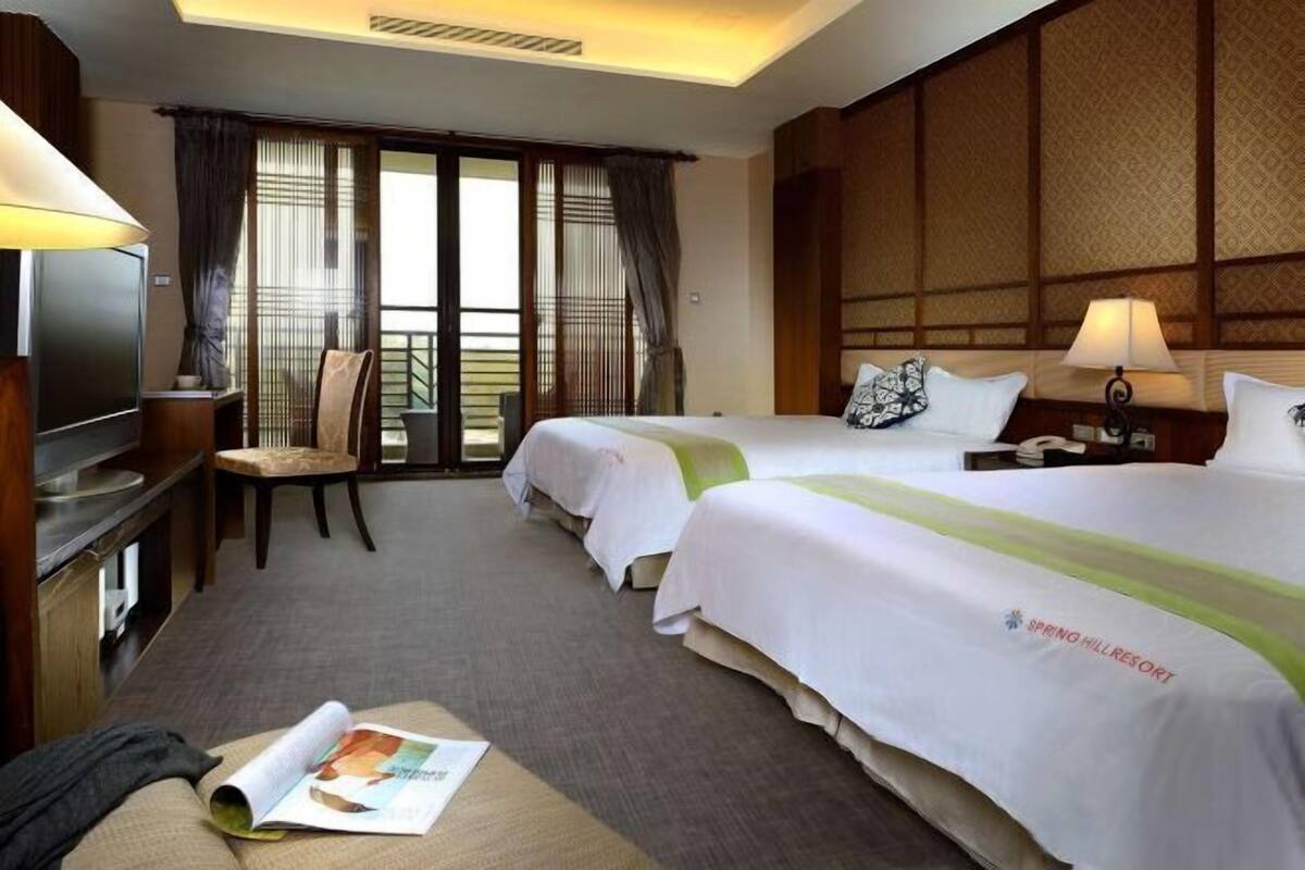 A hotel room with two beds, a TV, a desk, and a chair.