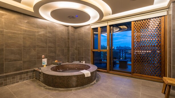 A modern spa room with a circular hot tub, a wooden partition, and a view of the outdoors. - Spring Hill Resort (Kaohsiung)