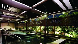 A spa area with a hot tub, seating, and a view of a garden. - Spring Hill Resort (Kaohsiung)