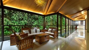 A spacious room with a wooden ceiling, a sofa set, and a large window offering a view of lush greenery. - Spring Hill Resort (Kaohsiung)