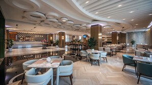 A spacious hotel lobby with a checkered floor pattern, a central bar area, and multiple seating arrangements including tables and chairs. - Rainbird International Hotel (Chengdu)