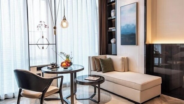 A modern living room with a sofa, a round table with chairs, and a decorative plant. - Rainbird International Hotel (Chengdu)