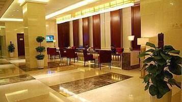 A hotel lobby with a reception desk, seating area, and a large plant.