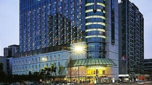 A modern hotel with a curved facade, multiple floors, and a prominent entrance with glass doors. - Rainbird International Hotel (Chengdu)