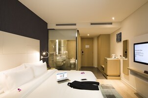 A hotel room with a bed, a laptop, a smartphone, and a robe on the bed.