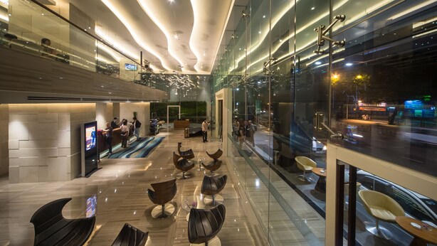 A modern hotel lobby with a reception desk, seating area, and large windows offering a view of the street. - Liberty Central Saigon Riverside (Ho Chi Minh City)