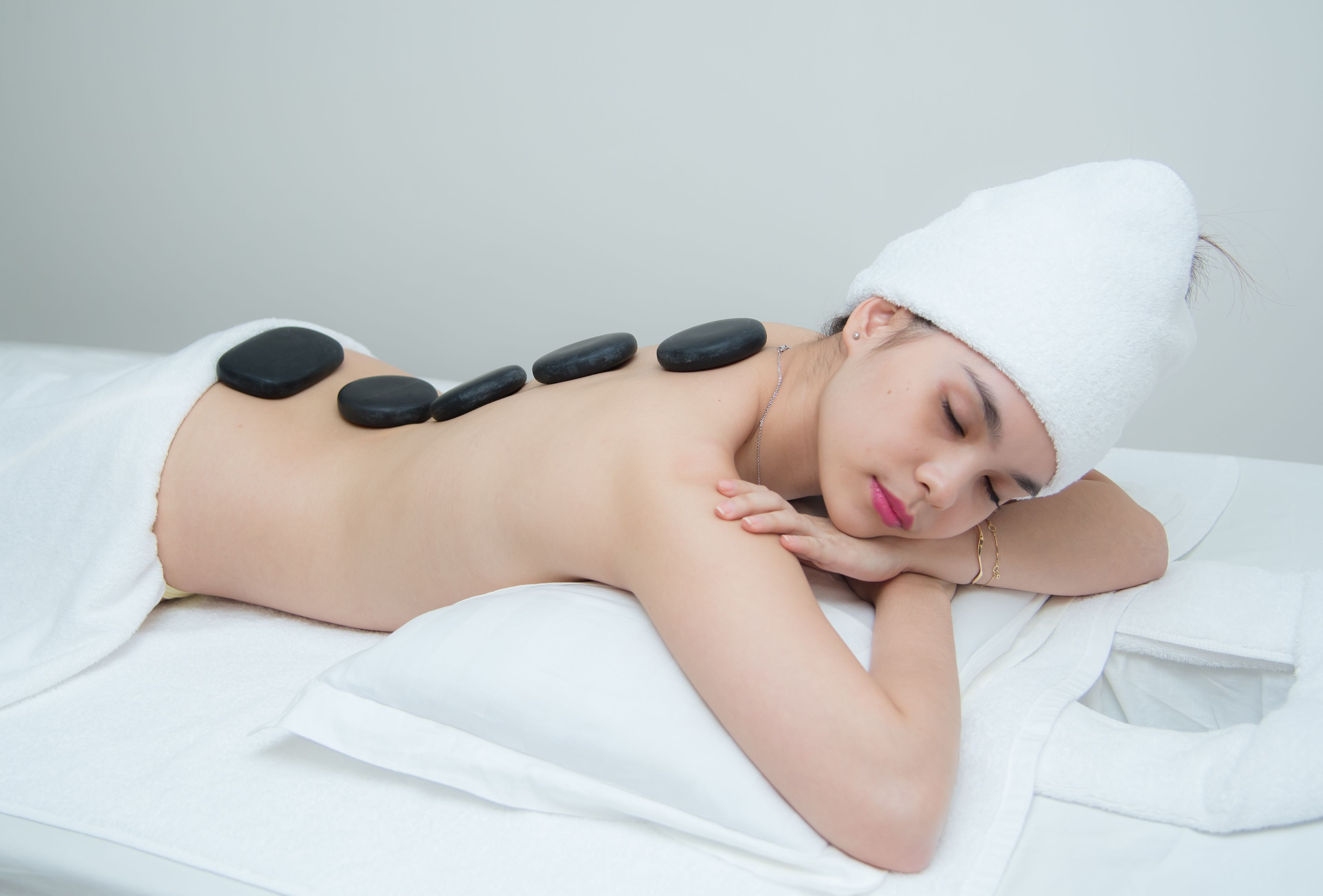A person receiving a back massage with stones.