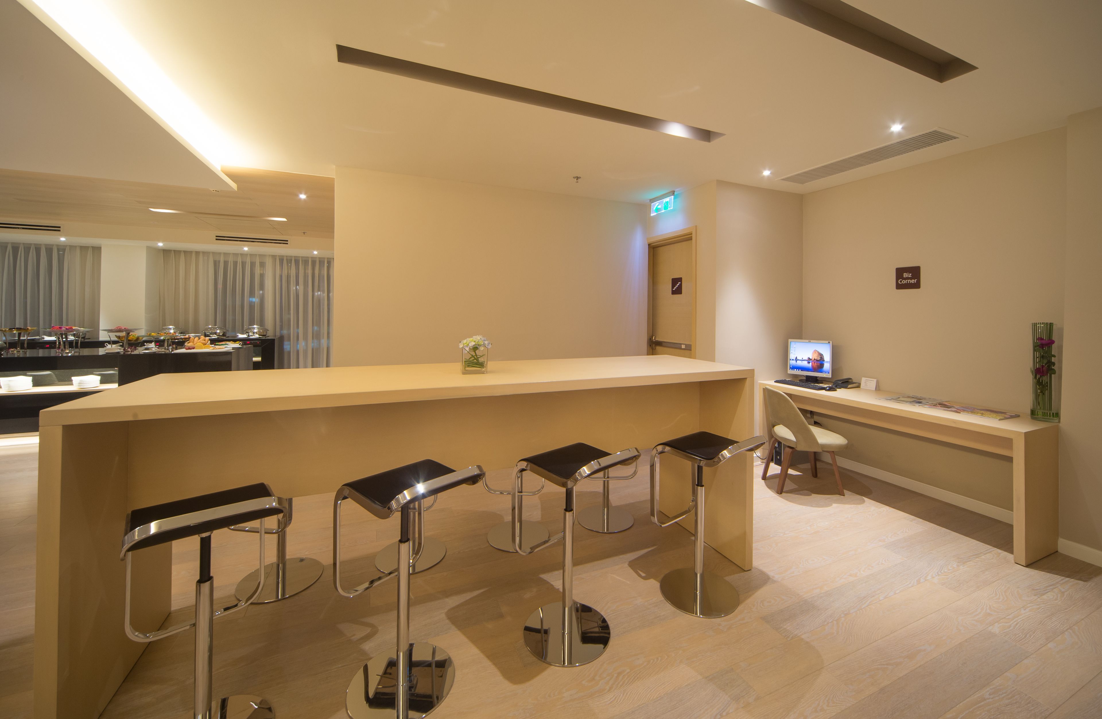 Una moderna zona de recepción con mostrador, taburetes de bar, un escritorio con computadora y un espacio de estar.
