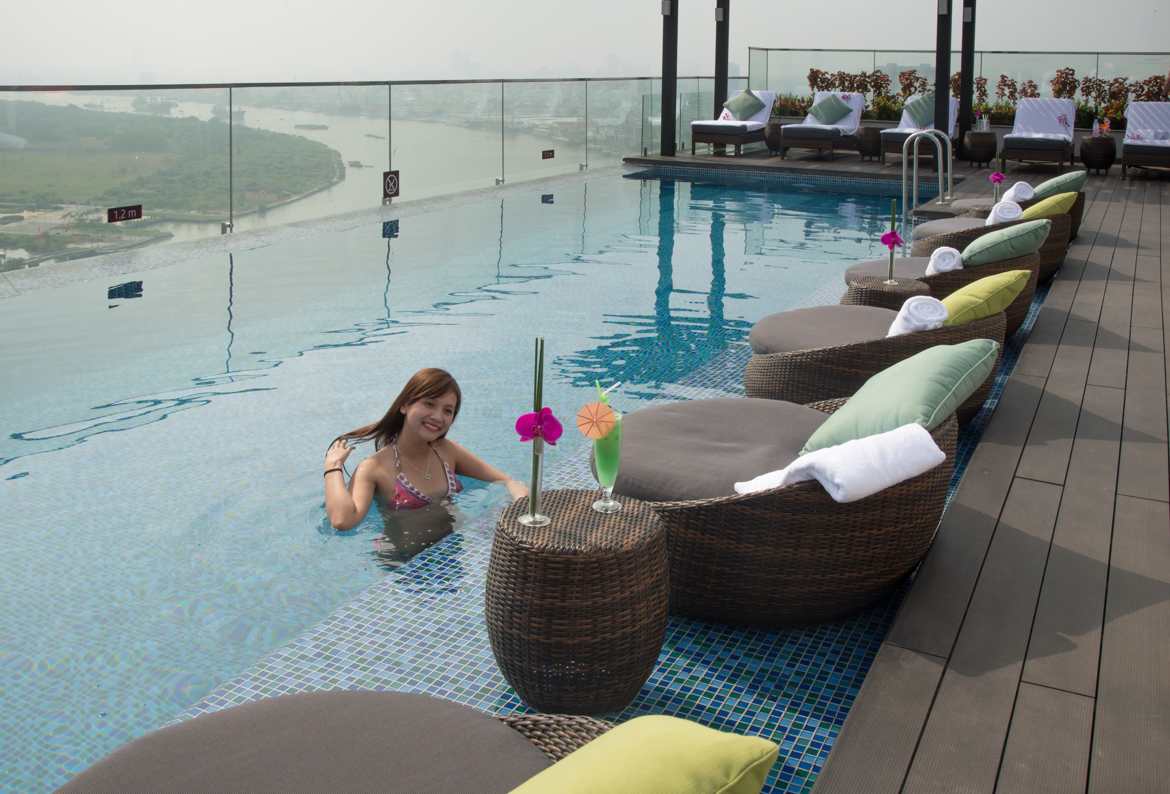 A pool area with lounge chairs and a view of a river.