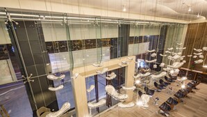 A modern interior with a glass wall, multiple hanging chairs, and a seating area with tables. - Liberty Central Saigon Riverside (Ho Chi Minh City)
