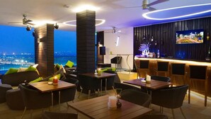 A rooftop bar with tables and chairs, a TV screen, and a city view at night. - Liberty Central Saigon Riverside (Ho Chi Minh City)