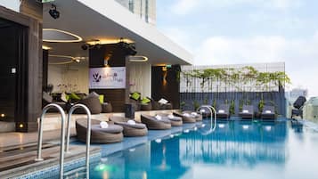 Un área de piscina moderna al aire libre con sillones de descanso y un cartel que dice 'Kali Night'.