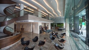 A spacious lobby with a curved staircase, modern seating, and a glass facade. - Liberty Central Saigon Riverside (Ho Chi Minh City)