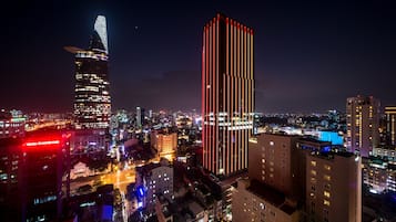 A cityscape at night with illuminated buildings, including a tall skyscraper with a distinctive top and a building with vertical red lights.