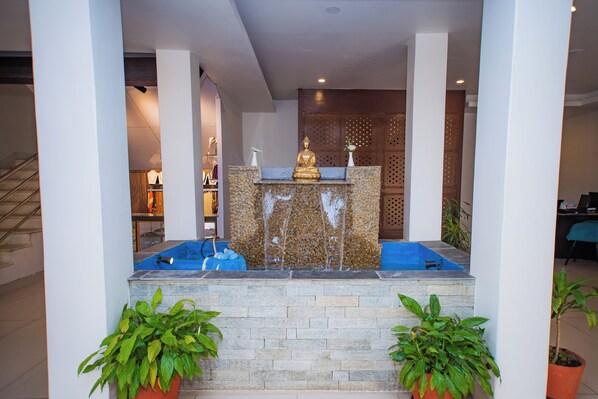 A reception area with a Buddha statue, a fountain, and potted plants. - Hotel Pokhara Village & SPA (Pokhara)