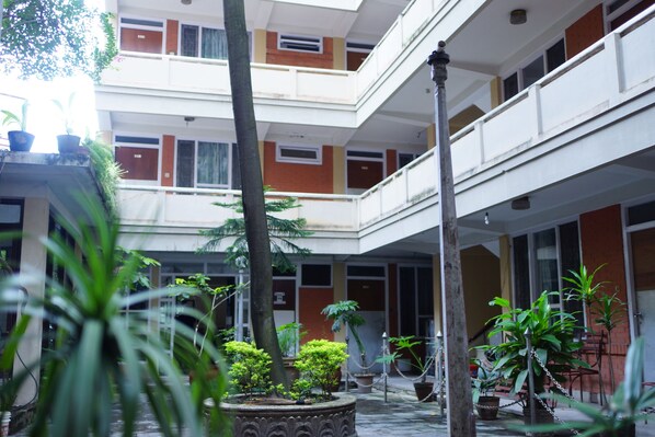Un immeuble à plusieurs étages, doté de balcons, de plantes en pot et d’une colonne centrale.