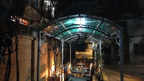 A covered outdoor dining area with tables and chairs, surrounded by plants and a brick wall. - Hotel Blue Diamond (Kathmandu)