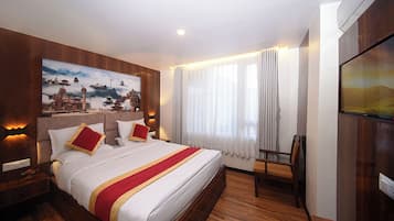 Una habitación de hotel con una cama grande, un cuadro en la pared, un televisor y una silla.