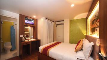 A hotel room with a bed, a desk, a TV, and a shower.