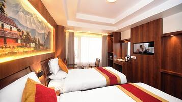 Ein Hotelzimmer mit zwei Betten, einem Fernseher, einem Schreibtisch und einem Bild an der Wand.