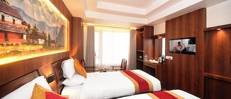 A hotel room with two beds, a TV, a desk, and a painting on the wall.