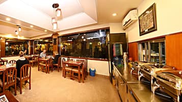 Un restaurante con mobiliario de madera, una zona de bufé y un ventanal grande.