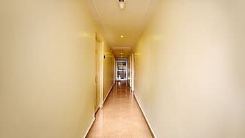 A narrow, well-lit hallway with a polished floor, leading to a door at the end.