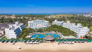 Un resort con piscina central, varias construcciones y zona de playa.