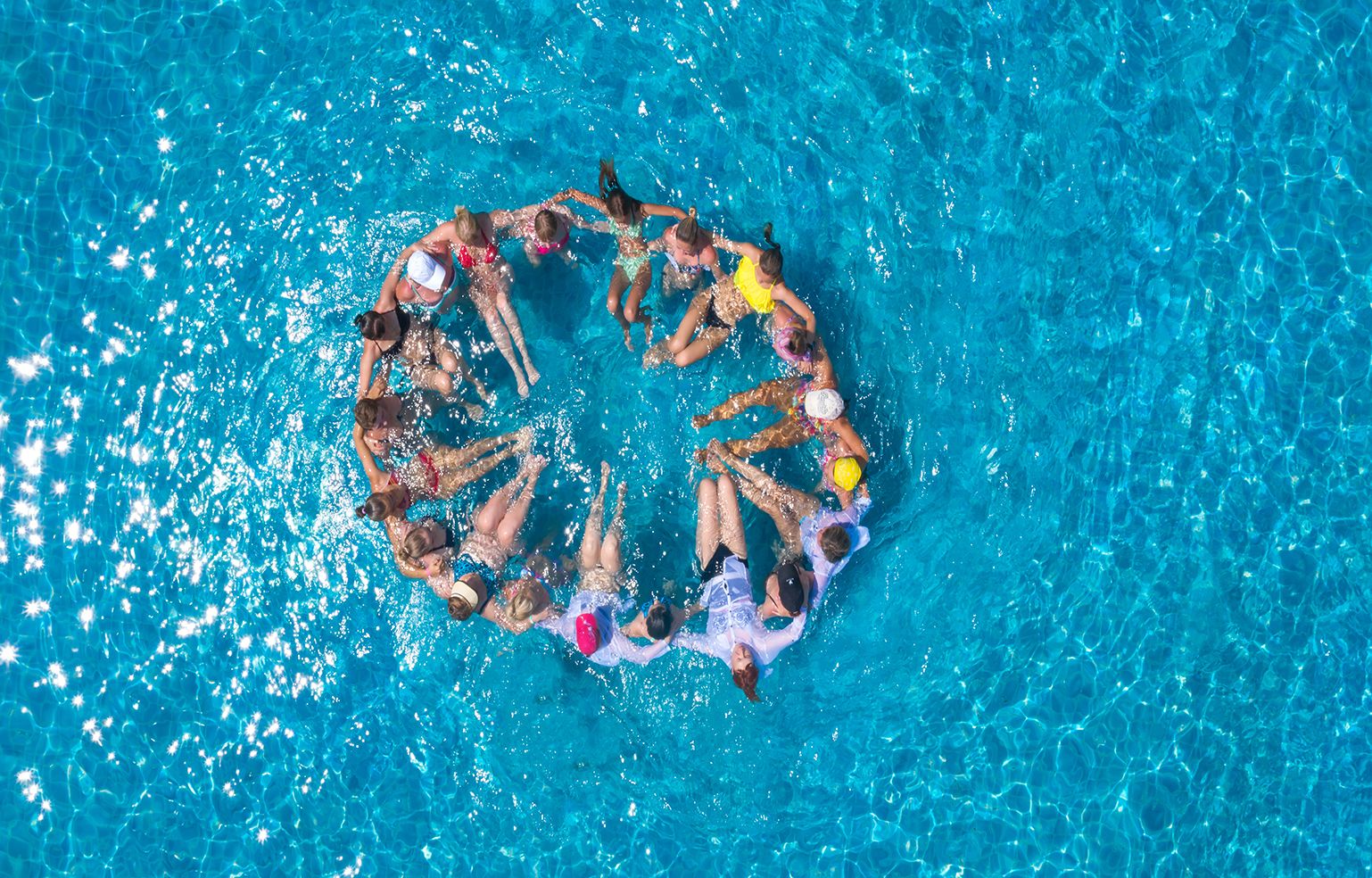 A circular arrangement of people in a swimming pool.