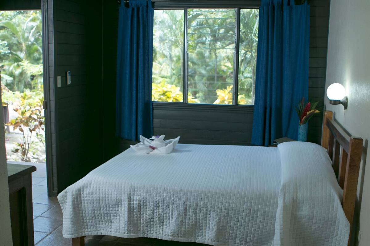 Un lit bien fait, avec une couette matelassée blanche et une serviette pliée posée sur la tête de lit.