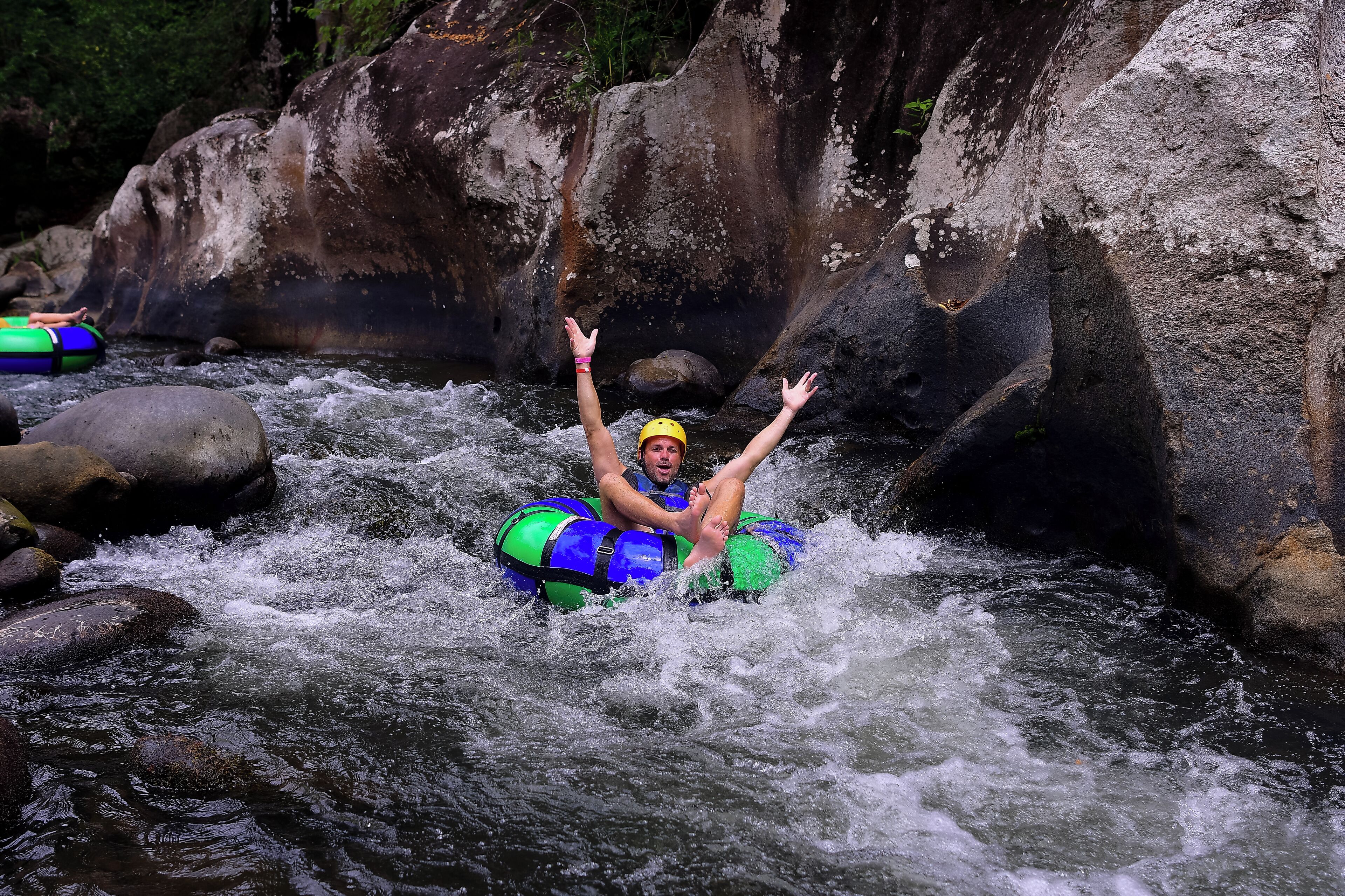 A person in a raft navigating a river with rocks and rapids.
