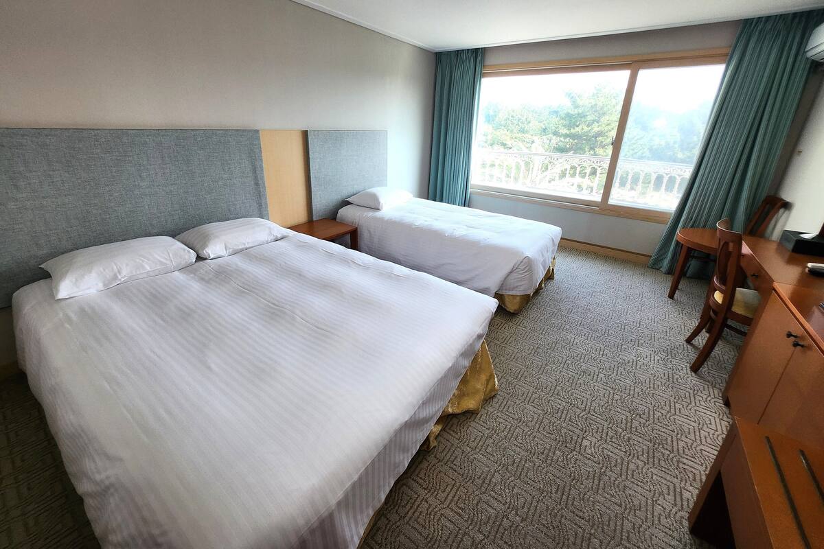 Une chambre d’hôtel avec deux lits, un bureau et une chaise.