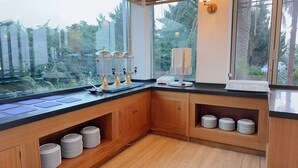 A kitchen with wooden cabinets, a black countertop, and a view of greenery outside.