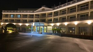 A multi-story hotel with a central entrance, balconies, and a well-lit facade.