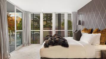 Une chambre moderne avec un grand lit, une vue à travers la porte vitrée et un motif géométrique sur le mur.