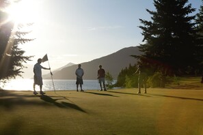 A golf course with a flag, a flag holder, and three golfers.