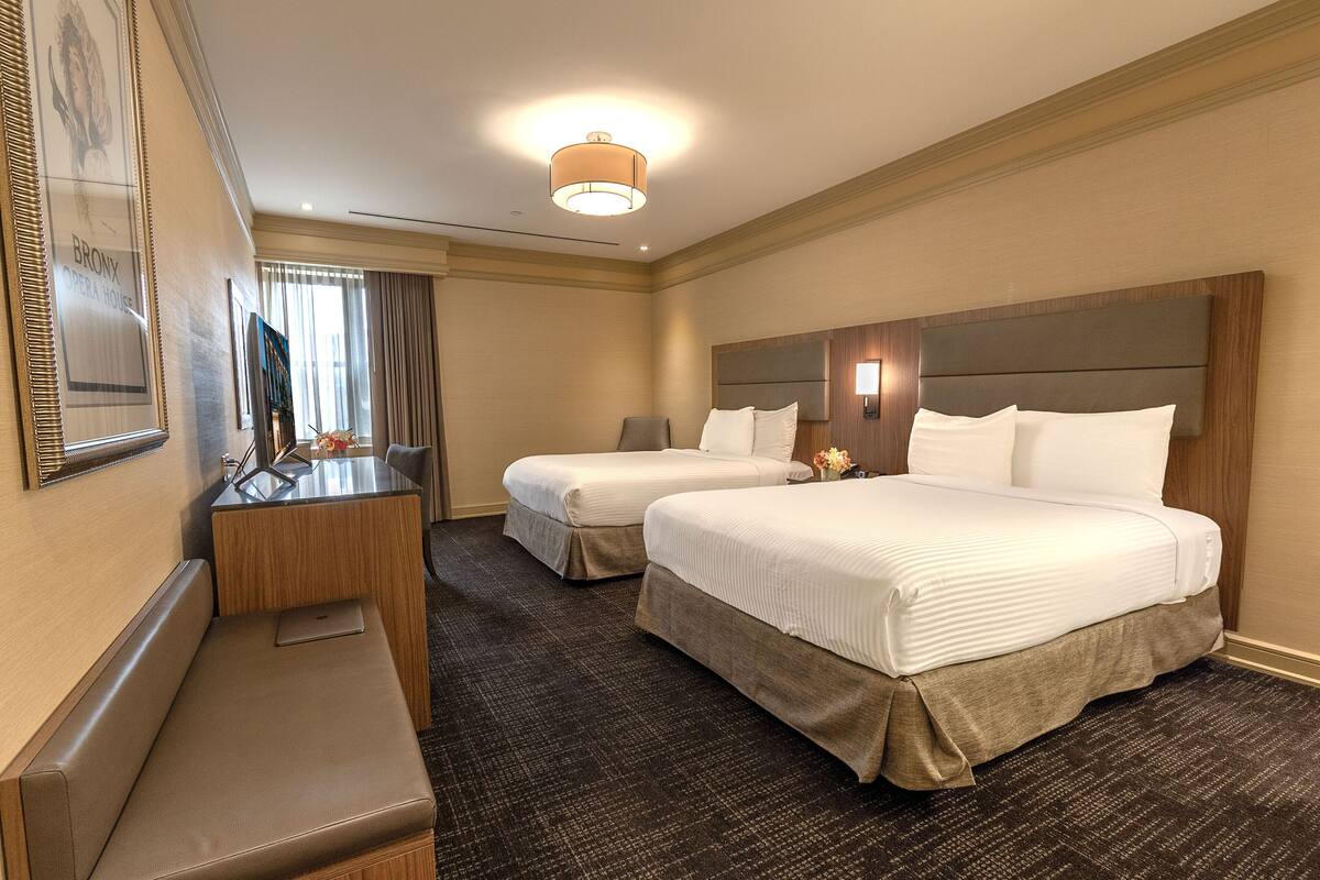 Une chambre d’hôtel avec deux lits, un bureau et un banc.
