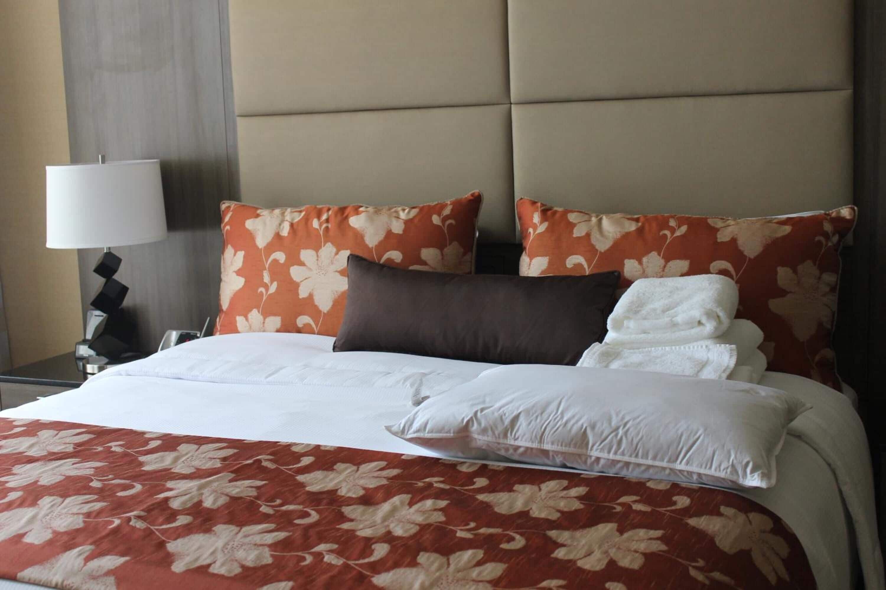 A hotel room with a bed, a nightstand, and a lamp.