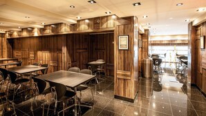 A modern restaurant with wooden paneling, polished black marble floors, and contemporary furniture. - Opera House Hotel (Bronx)