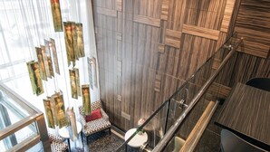 A modern interior with a staircase, a seating area with patterned cushions, and a wall with a geometric design. - Opera House Hotel (Bronx)