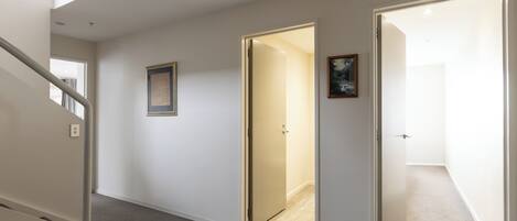 A hallway with a staircase, a door leading to another room, and a framed picture on the wall.