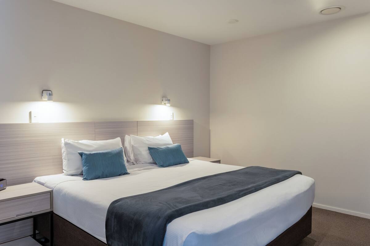Een hotelkamer met een bed, nachtkastjes en wandlampen.