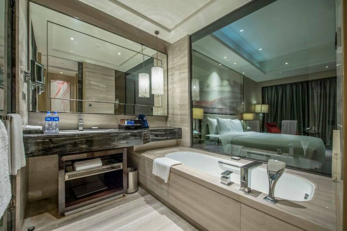 Ein modernes Badezimmer mit großem Spiegel, einer Badewanne, einem Waschtisch und einer Toilette.