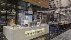 Un restaurant moderne doté d’un comptoir central, d’un chef et proposant une variété de plats.